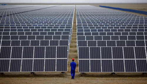 Apple Investasi untuk Pembangkit Listrik Tenaga Surya 2 A worker inspects solar panels at a solar farm in Dunhuang, 950km northwest of Lanzhou, Gansu Province