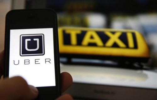 An illustration picture shows the logo of car-sharing service app Uber on a smartphone next to the picture of an official German taxi sign